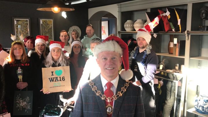The Town Mayor wears a santa hat and mayoral chain in front of a group of local traders