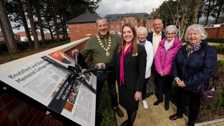 The Town Mayor prepares to remove a ribbon from a board, surrounded by other people