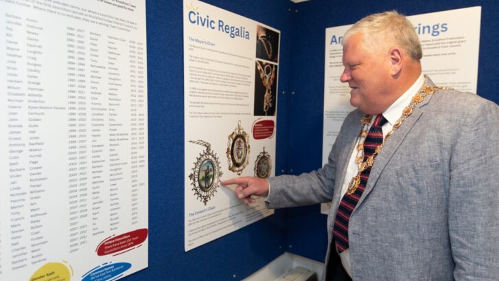 Town Mayor Cllr Colin banks points to the Mayoress medallion on the exhibition panel