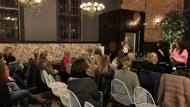 A group of people sat down listening to a woman giving a talk
