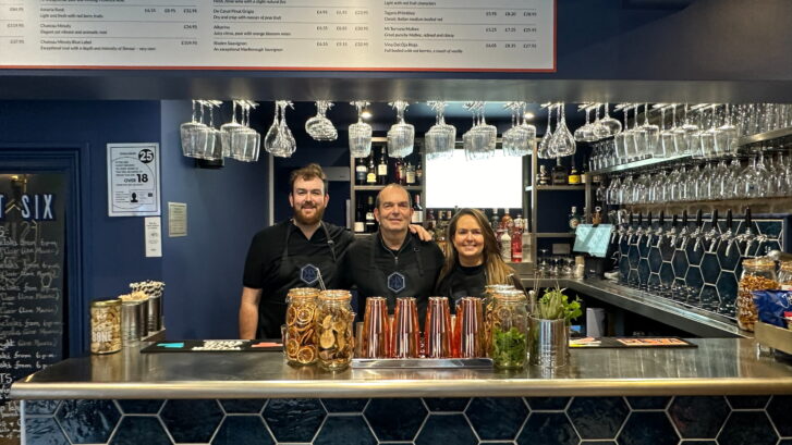 Staff of SIX stood behind the bar of new restaurant smiling.