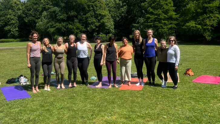 A group stood in the park on Yoga mats