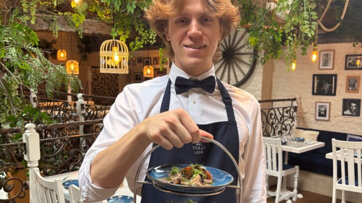 charlie berrisford stood holding a plate of food served at the stolen lamb