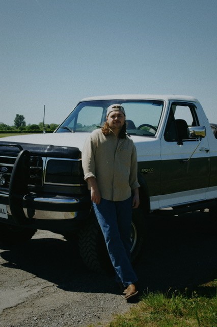Jake O'Neill leaning against a truck outside on a sunny day