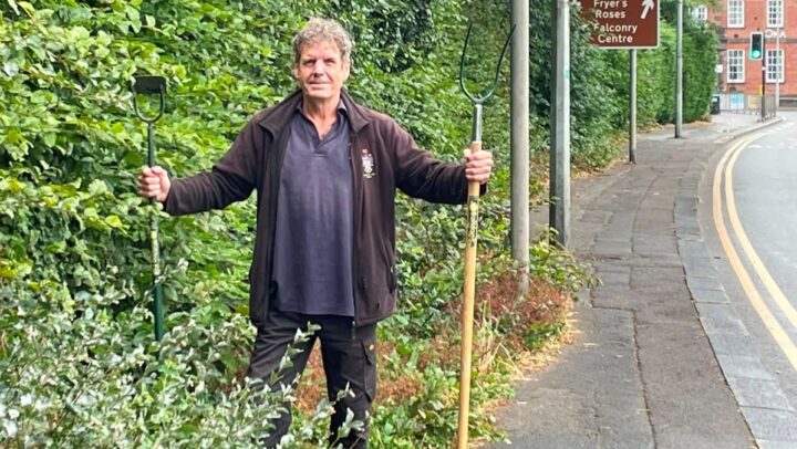 Knutsford Town Ranger holding a pitch fork in overgrown vegetation
